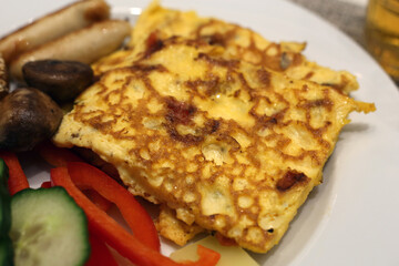 Delicious omelette with veggies, bread and sausages. Fresh and yummy hotel breakfast in Switzerland.