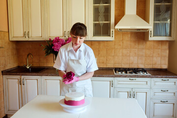 Housewife or confectioner chef decorating delicious birthday or wedding cake with peony flowers.