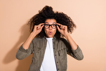 Portrait of attractive trendy stunned amazed girl touching specs pout lips isolated over beige...