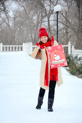View of a young cheerful woman with New Year's packages in her hands against the backdrop of a winter street in the city. Christmas shopping concept