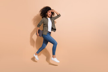 Fototapeta na wymiar Full length body size view of pretty cheerful girl jumping carrying laptop finding way isolated over beige pastel color background