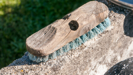 Cepillo  rústico de madera con cerdas azules encima de pila de piedra en jardín