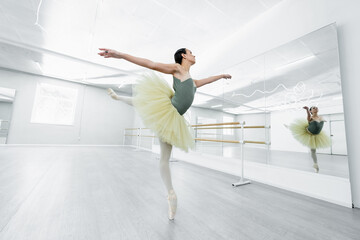 Fototapeta na wymiar full length view of graceful ballerina dancing during repetition in studio