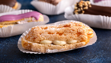 Beautiful delicious French eclairs with custard, covered with multi-colored icing.