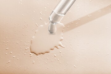 A drop of cosmetic oil falls from the pipette on the desk