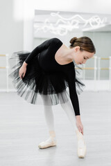 preteen girl in black tutu training in ballet school