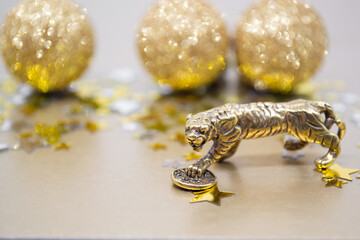 A bronze figure of a tiger with a coin - the symbol of the Chinese new year 2022 on a background of stars, golden shiny balls, copy space. Wishes of good luck, financial well-being and wealth