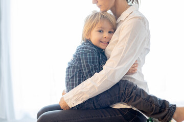 Fototapeta premium Portrait of mother and child, hugging on a back lit white background