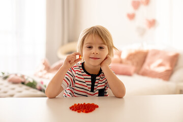 Cute little child, toddler boy, eating alfa omega 3 child suplement vitamin pills at home