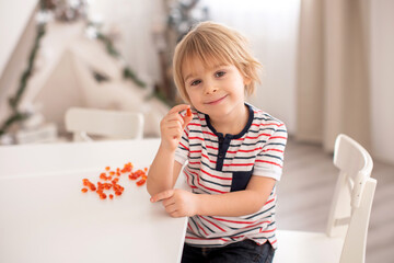 Cute little child, toddler boy, eating alfa omega 3 child suplement vitamin pills at home