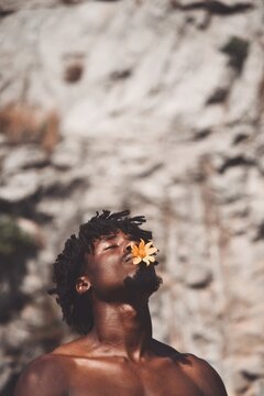 Shirtless man with flower in mouth