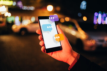 Female hand holding smartphone with chat box icons