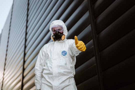 man in a protective suit in front of a building with yellow glowers