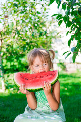 Child eating watermelon in the garden, summer time in park