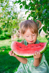 Child eating watermelon in the garden, summer time in park