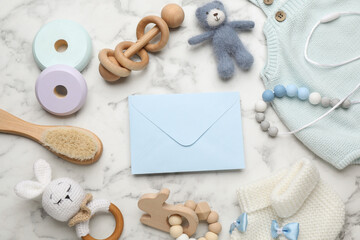 Fototapeta na wymiar Baby shower party. Envelope surrounded by stuff for child on white marble background, flat lay