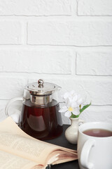 Morning tea. An open old book on the kitchen table and a cup of tea. Leisure reading in a cozy loft-style room