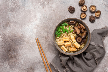 Asian vegetarian ramen noodle soup with roasted tofu cheese, chives and shiitake mushrooms in a...