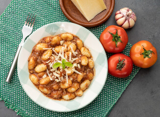 Italian pasta gnocchi on a plate with tomato sauce, basil and parmesan cheese