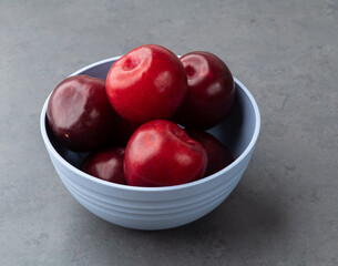 Plums in a bowl over stone background