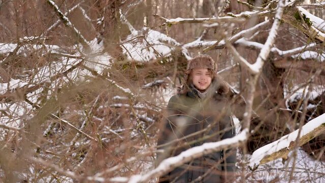 4k video portrait of cute happy smiling kid standing behind bare branches of snowy trees in winter forest