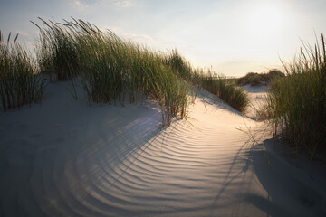 The warm setting sun caresses the soft sand hills and dunes at the beach from the island of Juist...