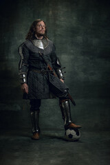 Portrait of medieval warrior or knight with dirty wounded face posing with football ball isolated...