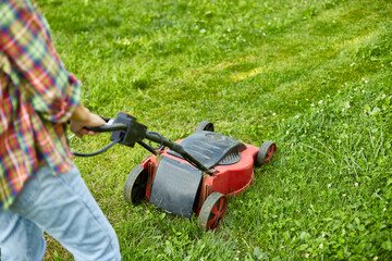 unrecognizable Woman mows the lawn with a lawn mower grass at home garden, gardener woman working
