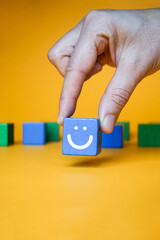 Customer service experience and business satisfaction survey. A hand holding wood block with smiley face.