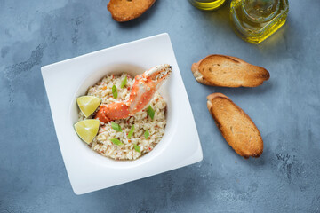 Plate of risotto with crab meat and baguette on a grey concrete background, top view, horizontal shot