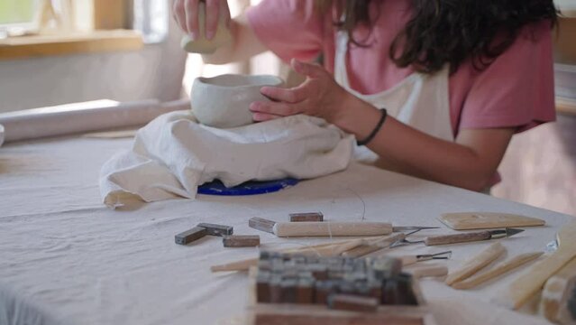 talented and skilled woman is making ceramic bowl in pottery workshop