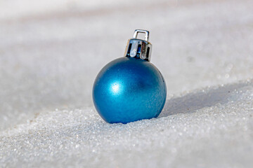 one blue christmas tree ball on white snow