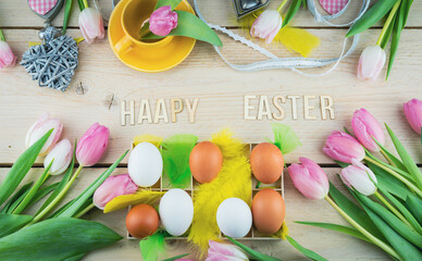 Happy easter karta, na drewnianym stole ułożone jajka, tulipany, żółte piórka, dekoracja wielkanocna. - obrazy, fototapety, plakaty