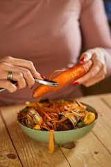 Women scraps peels carrots vegetable peeling, throws in compost bucket, organic composting