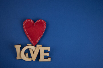 Love word, small hearts on dark blue paper background. Top view of Valentine's Day.