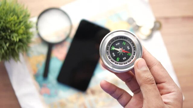 top view of holding a compus with travel map on table,