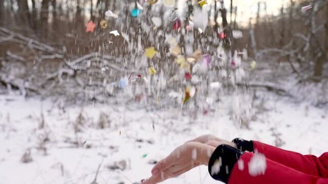 Female hands, beautiful colorful bright multicolor confetti on white snowy background. Christmas, Xmas, New Year celebration concept. Slow motion 4k stock video of woman throwing confetti and snow up