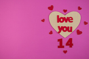 The word Love with small hearts against a pink paper background closeup