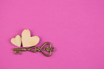 Pink background with two red hearts and a key for a congratulation Happy Valentine's Day.