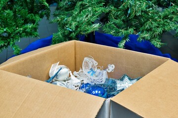 Packing away Christmas decorations after new year full box decorations by empty tree and skirt.	