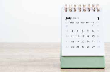 July 2022 desk calendar on wooden background.