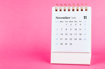 November 2022 desk calendar on pink background.