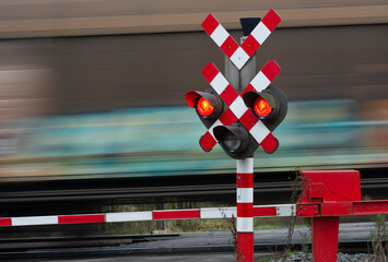 Train passes at crossing with red signal and closed barriers. 