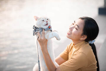 Beautiful black haired woman holding a beautiful orange cat Happily near the pool area
