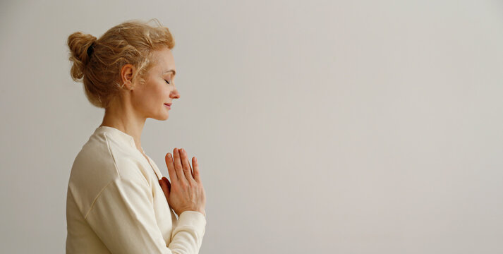 Sporty adult woman practicing yoga in the comfort of her own home. Fit middle aged yogini performing morning physical exercise routine at the living room. Interior background, copy space, close up.