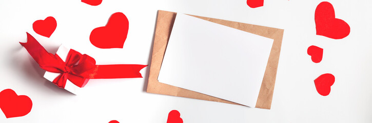 Blank card, envelope, paper hearts and gift box on white background, flat lay with copy space. Valentine's Day celebration. Romantic love letter for Valentine's day concept.