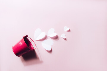 Valentine's Day background. White volumetric paper hearts and pink bucket on a nude pink background. Valentine's Day concept. Flat lay