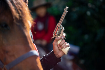 Cowboy's hand gun revolver, blur the foreground with a horse.