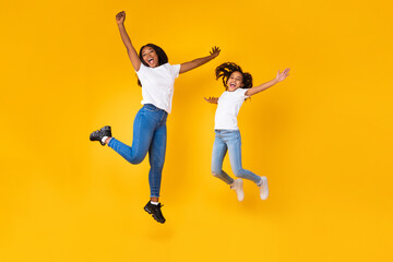 Fototapeta na wymiar Portrait of emotional black family of two jumping at studio