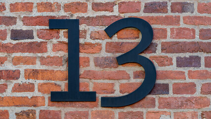 House number thirteen (13) on a red brick wall. High resolution photo.